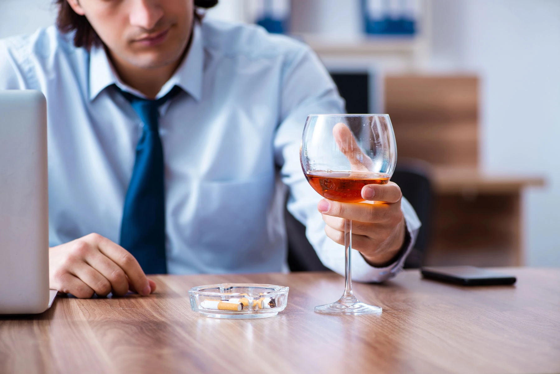 Osoba pijąca alkohol podczas spotkania towarzyskiego jako ilustracja szarej strefy picia i ukrytego problemu z alkoholem.