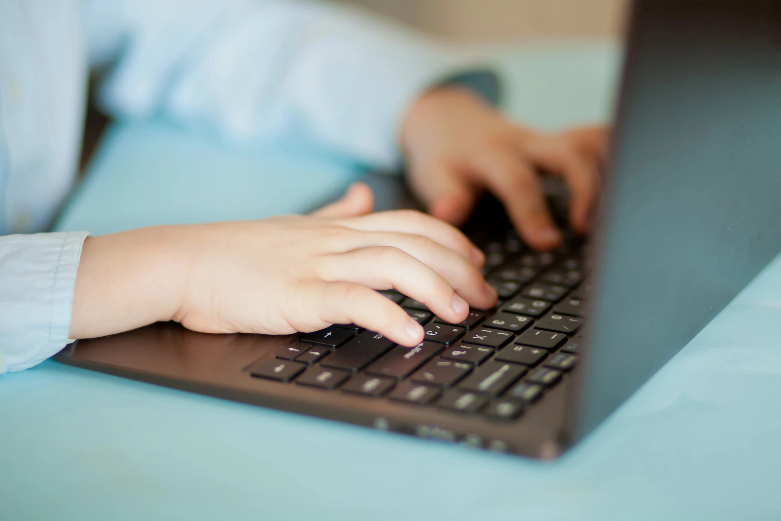 Dziecko korzysta z laptopa, co symbolizuje ryzyko e-hazardu wśród dzieci i młodzieży w internecie.